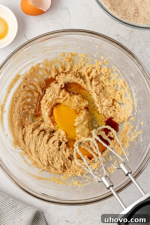overhead view of egg and vanilla added to creamed butter and sugar in a glass mixing bowl