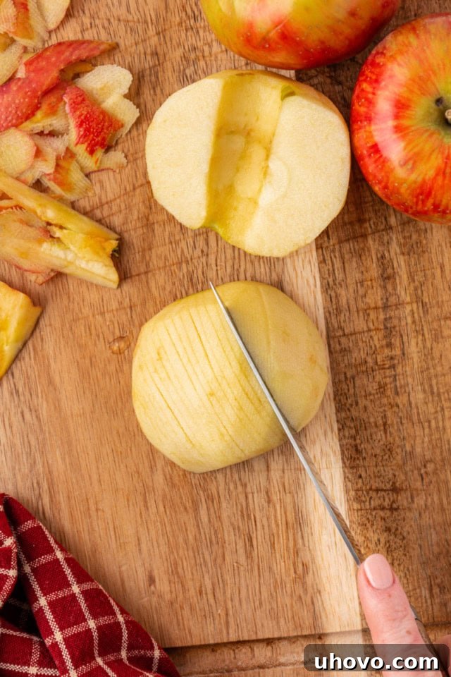 Overhead view of a fresh apple being precisely sliced for German apple cake, illustrating the technique of keeping slices attached at the base to form a fan shape.