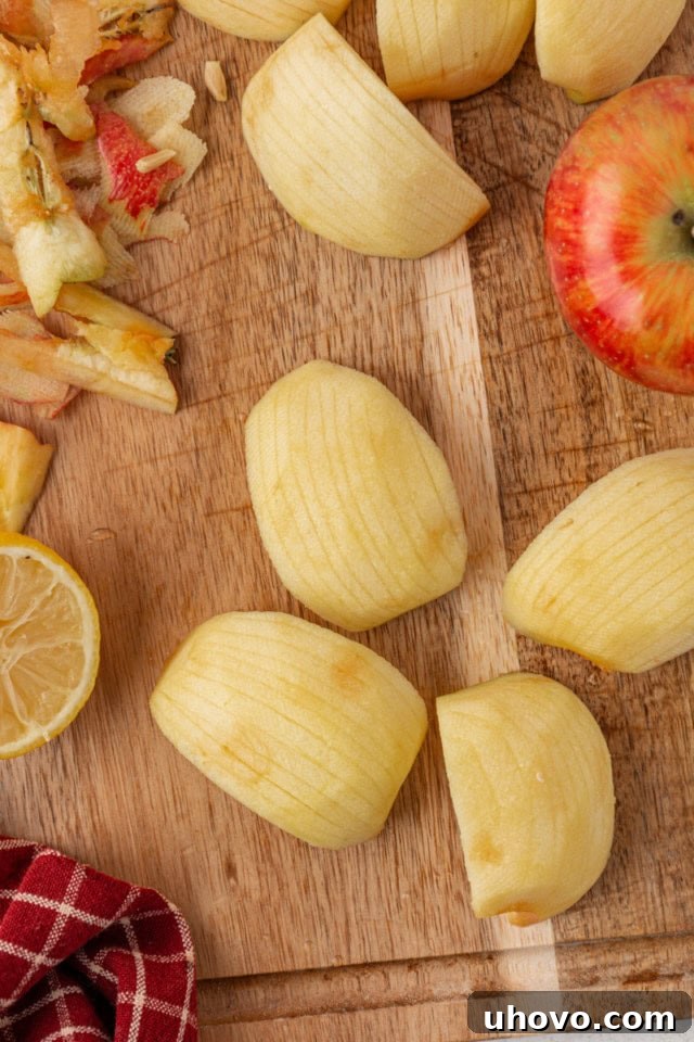 Overhead view of partially sliced apples, prepared for topping German apple cake, showing them lightly brushed with lemon juice to prevent any browning.