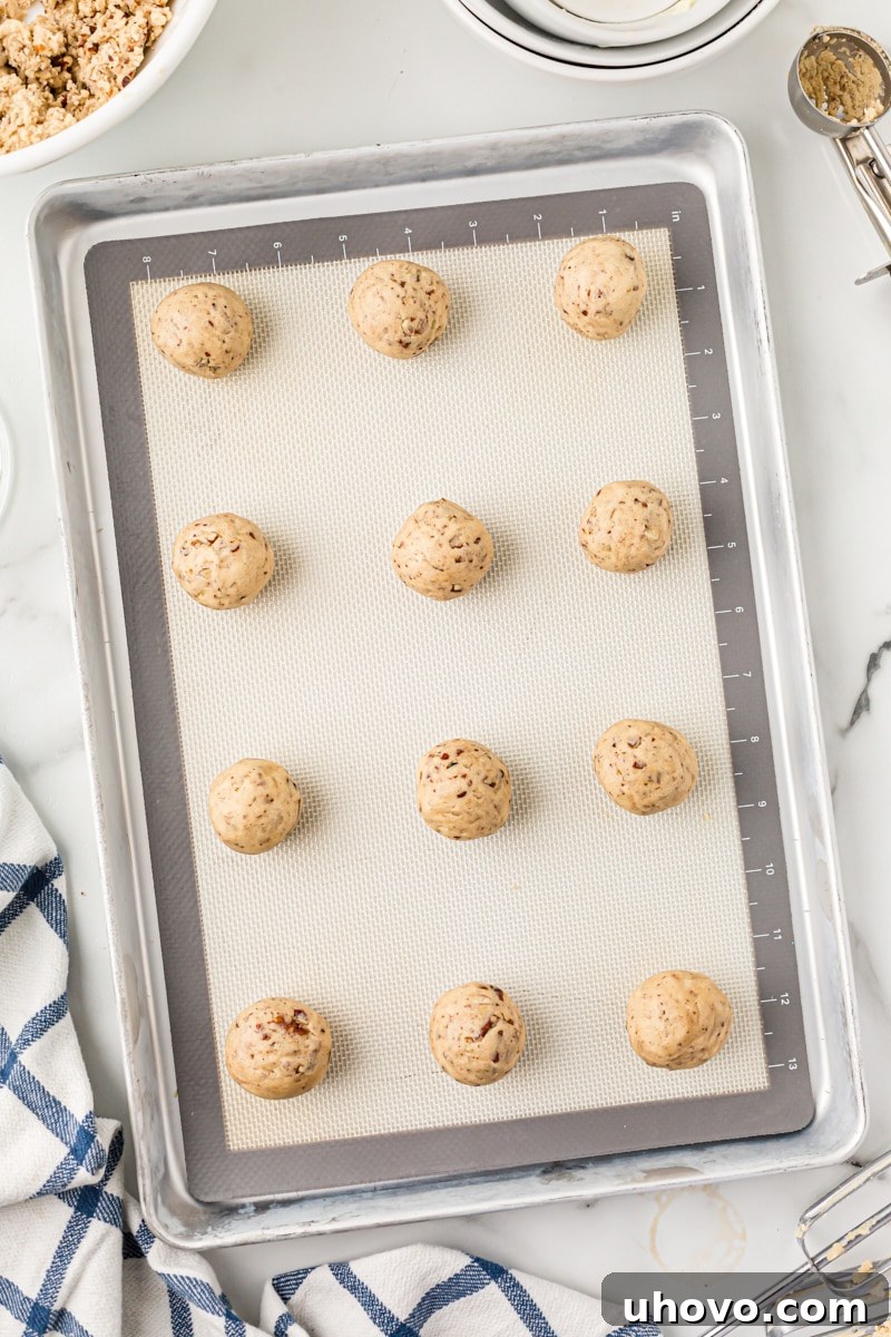 Overhead view of pecan sandies dough rolled into uniform balls and placed on a parchment-lined baking sheet.