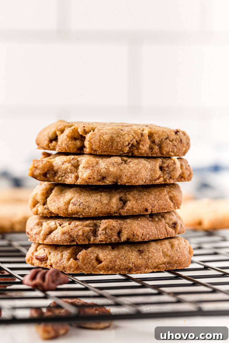 Stack of 5 pecan sandies on a wire cooling rack, perfectly golden and ready to enjoy. These classic pecan cookies practically melt in your mouth!