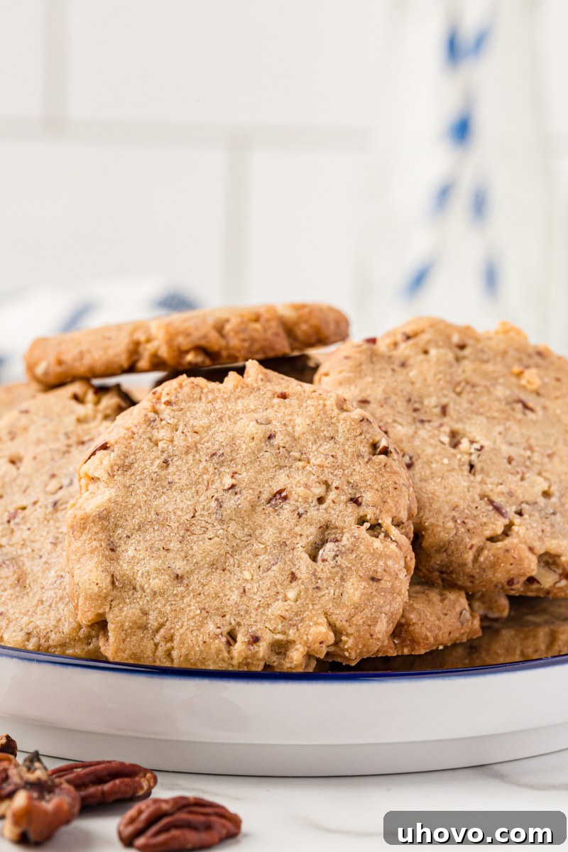 Plate of pecan sandies cookies, showcasing their golden brown edges and sandy texture. These classic pecan cookies practically melt in your mouth!