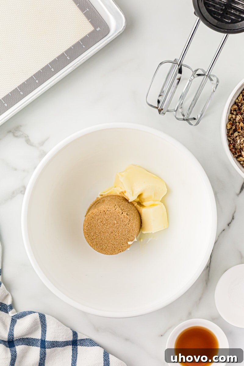 Overhead view of light brown sugar and softened butter in a mixing bowl, ready to be creamed for pecan sandies.