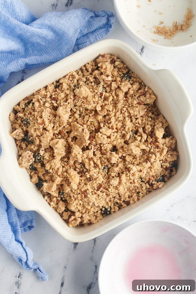 Overhead view of the blueberry crisp in the baking dish, fully assembled with the crumble topping, before baking.