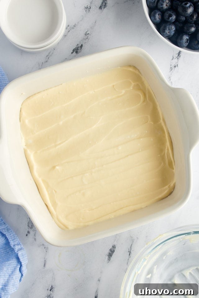 Overhead view of the unbaked cream cheese mixture spread evenly in a prepared baking dish.