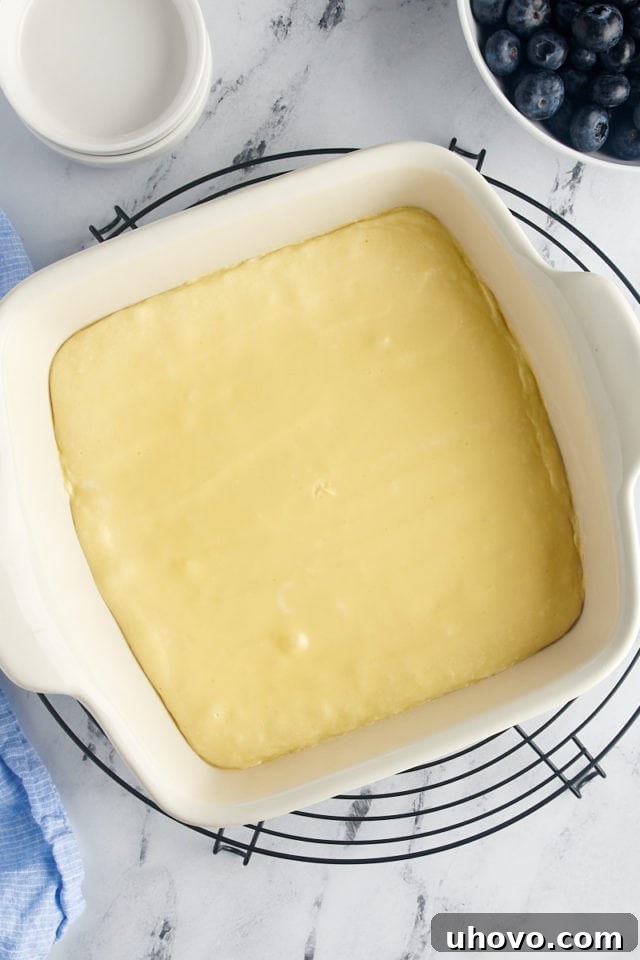Overhead view of the partially baked cream cheese layer, looking set and ready for the fruit.