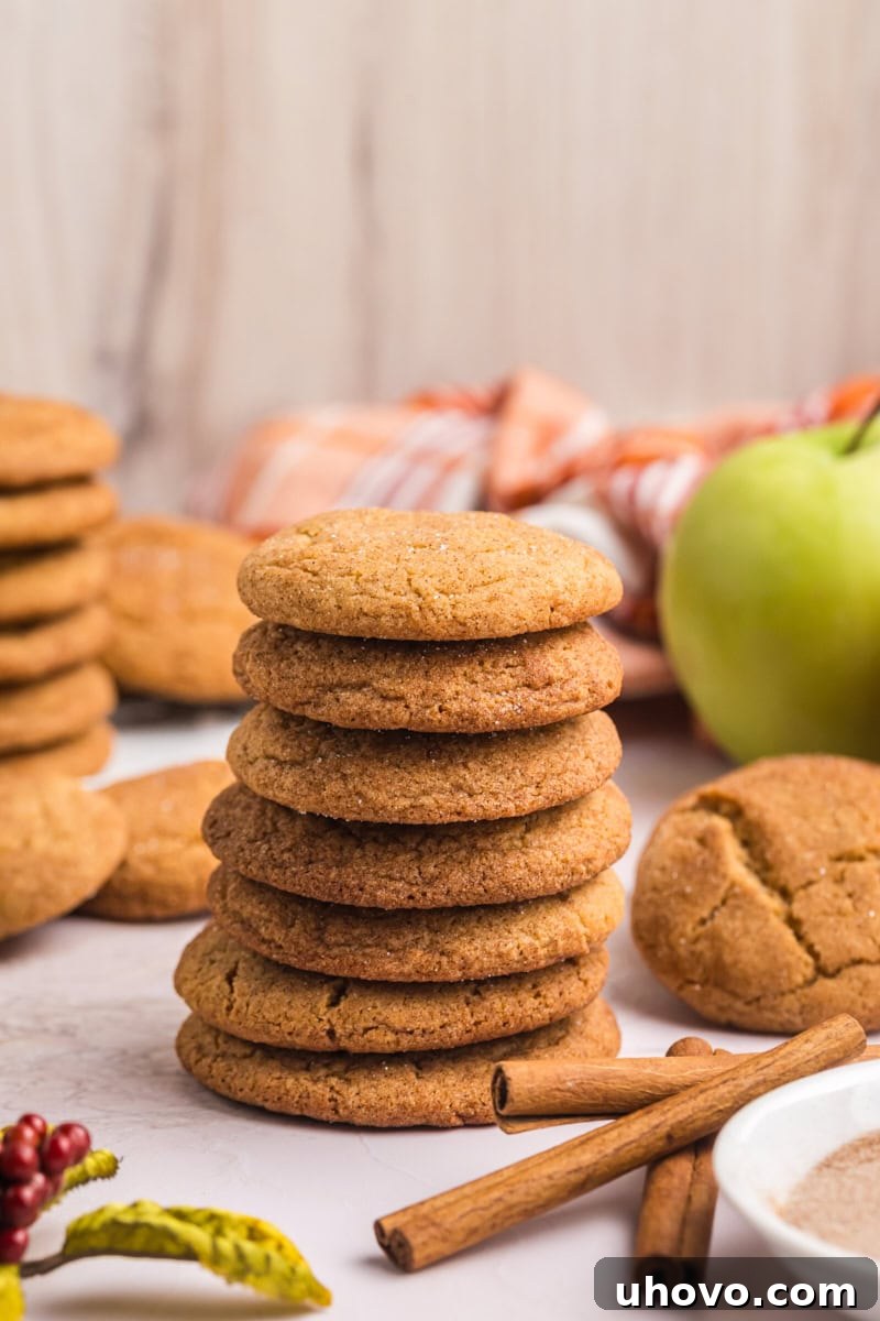 stack of several apple butter snickerdoodles with more cookies and apples in the background
