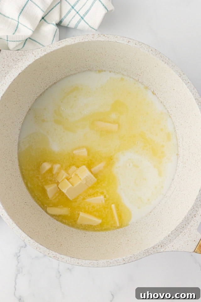 overhead view of water, milk, butter, sugar, and salt in a saucepan simmering gently on the stovetop, just before boiling