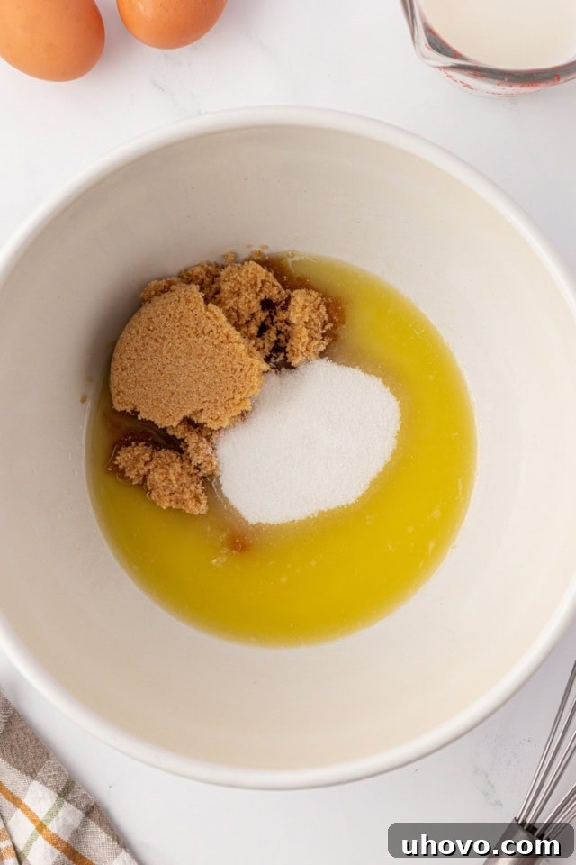 overhead view of melted butter, brown sugar, and sugar in a white mixing bowl