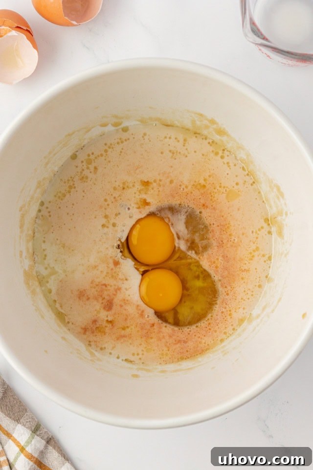 overhead view of eggs, milk, and vanilla added to partially mixed muffin batter