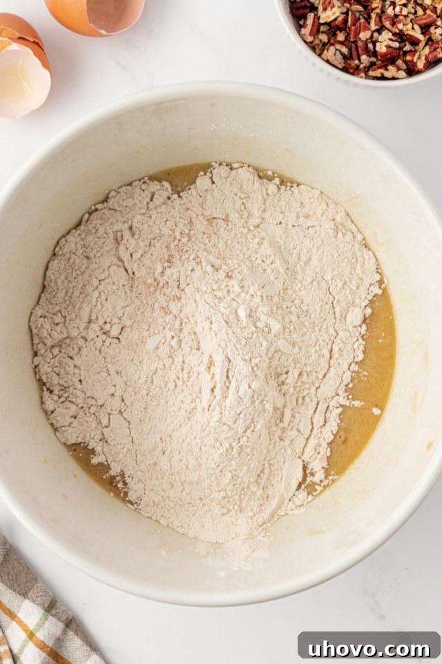overhead view of dry ingredients added to wet ingredients for pecan praline muffins