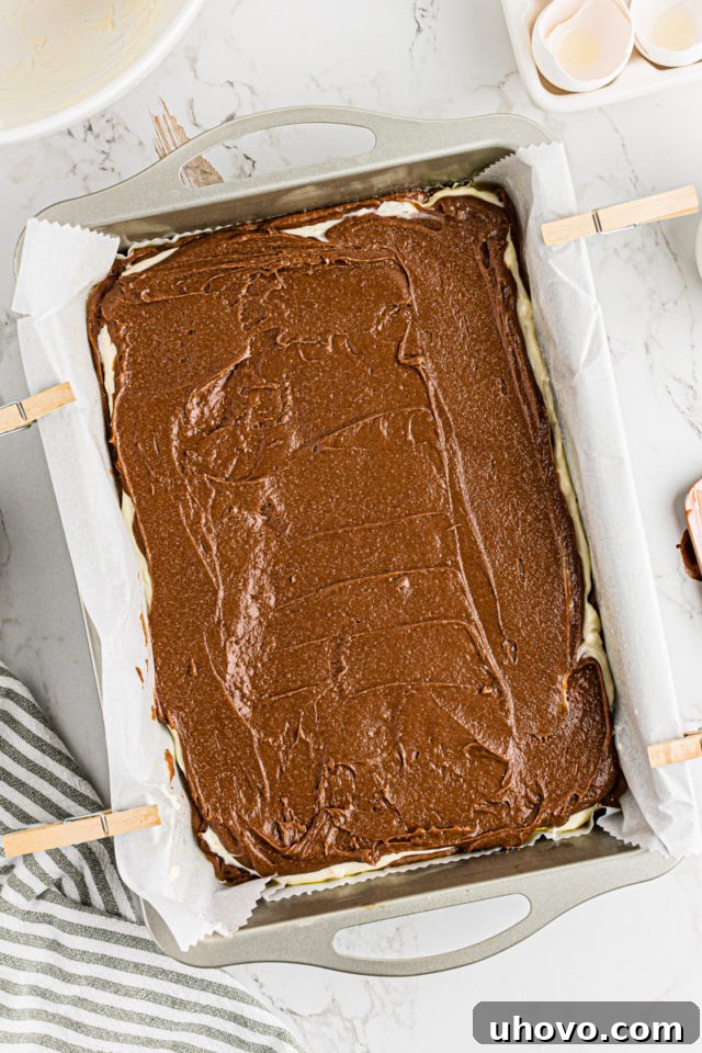 Overhead view of Irish cream brownies in pan before baking, with top brownie layer spread over the cream cheese.