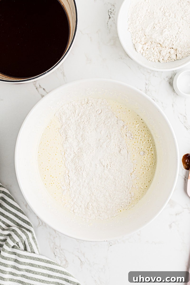 Overhead view of flour and salt added to wet ingredients for brownies.