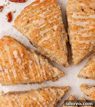 Overhead view of a beautifully arranged plate of maple pecan scones, golden-brown and drizzled with glaze, ready to be served.
