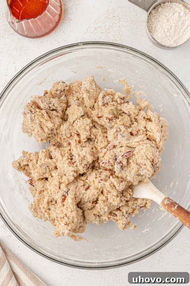 A cohesive, slightly shaggy maple scone dough rests in a glass mixing bowl, having just been combined.