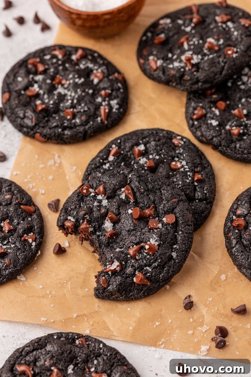 black cocoa cookies scattered over parchment paper on a white surface