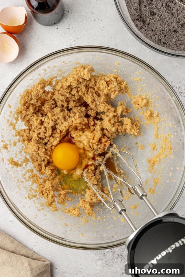 overhead view of egg added to creamed butter and sugar in a glass mixing bowl