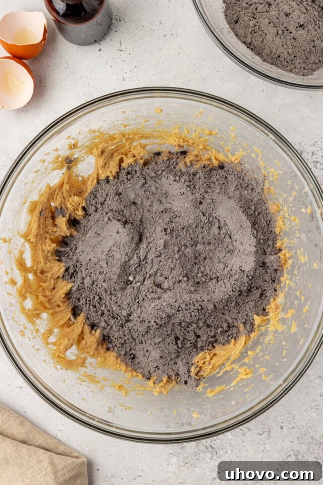 overhead view of dry ingredients added to wet ingredients for black cocoa cookies