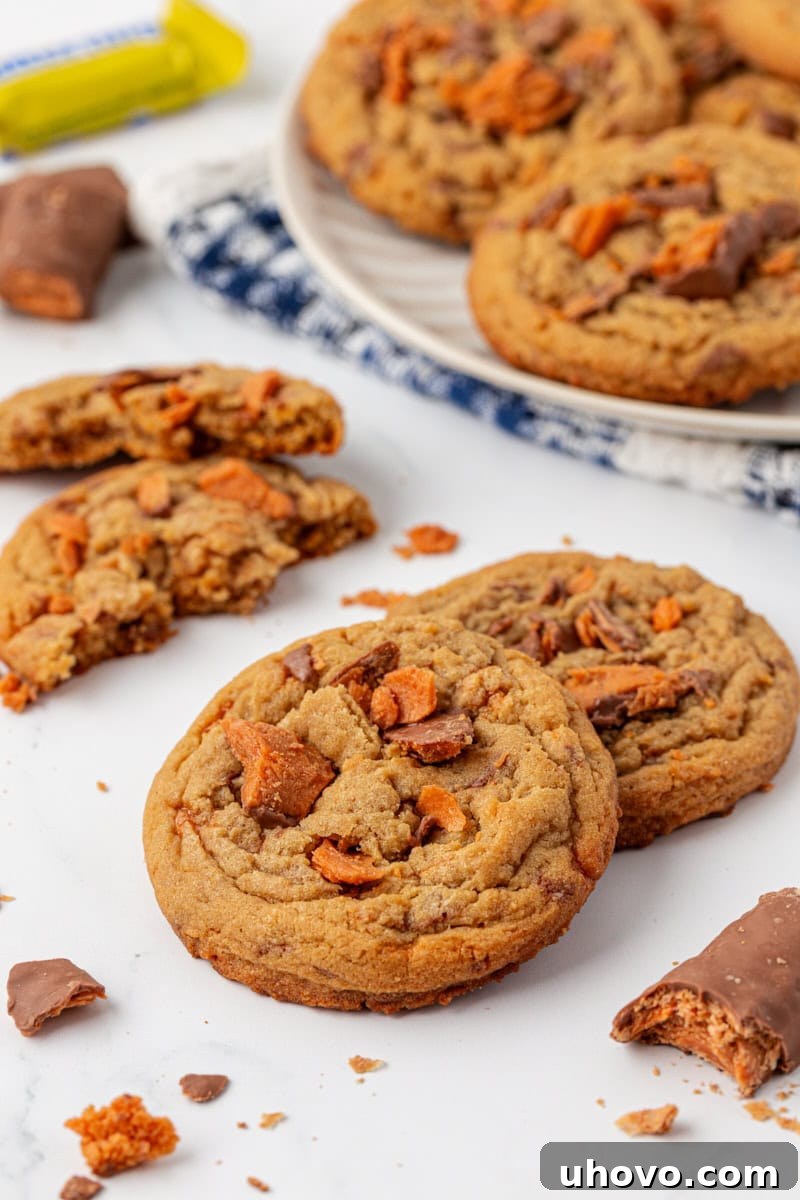 two Butterfinger cookies on a white surface with more cookies in the background