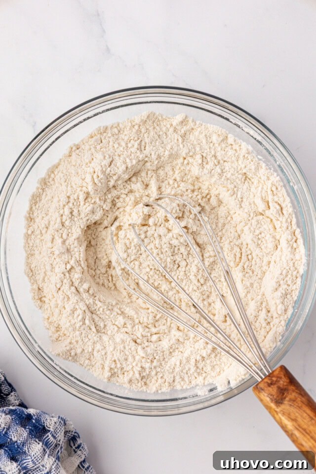 overhead view of flour, baking soda, and salt whisked together in a glass mixing bowl