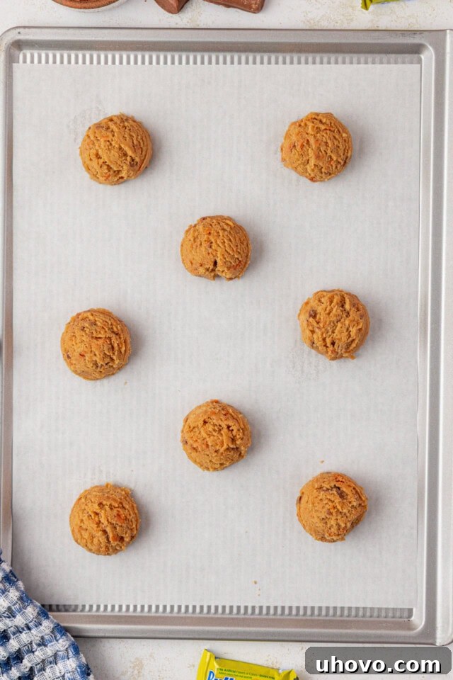 overhead view of Butterfinger cookie dough scooped onto a parchment-lined baking sheet, ready to go into the oven