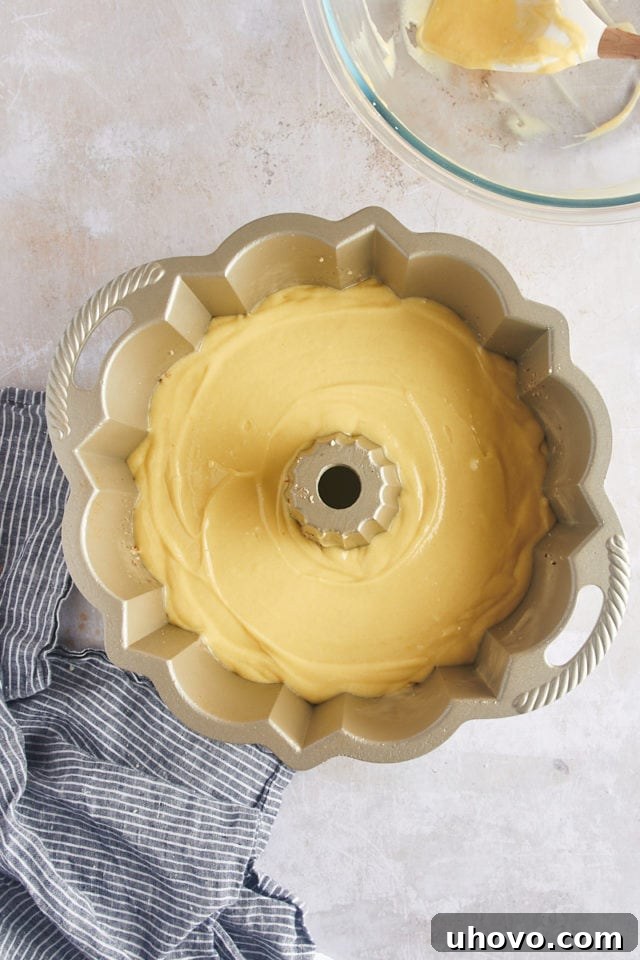Overhead view of the smooth rum cake batter carefully poured into the prepared Bundt pan, covering the pecans at the bottom.