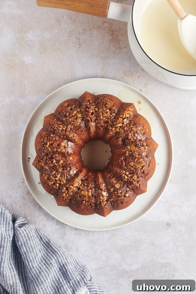 Overhead view of the complete rum cake on a platter, glistening with its finished glaze and topped with pecans.