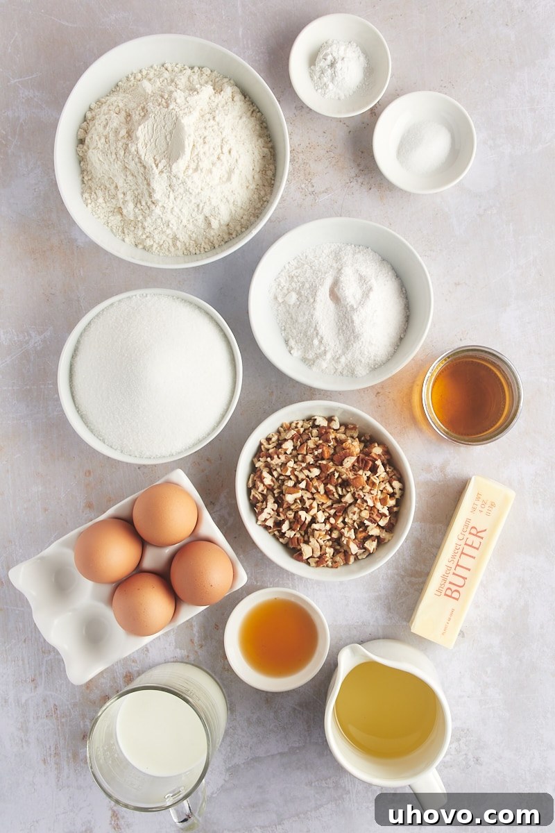 Overhead view of all the dry and wet ingredients laid out for making the rum cake, including flour, sugar, butter, eggs, and a bottle of rum.