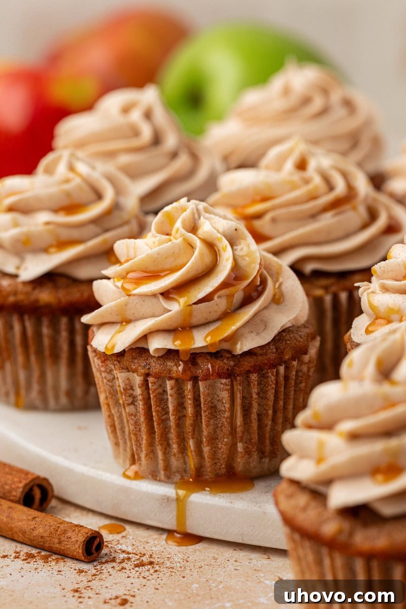 Delightful apple cupcakes topped with creamy spiced cream cheese frosting and a caramel drizzle, beautifully arranged on a marble serving tray for a perfect fall treat.