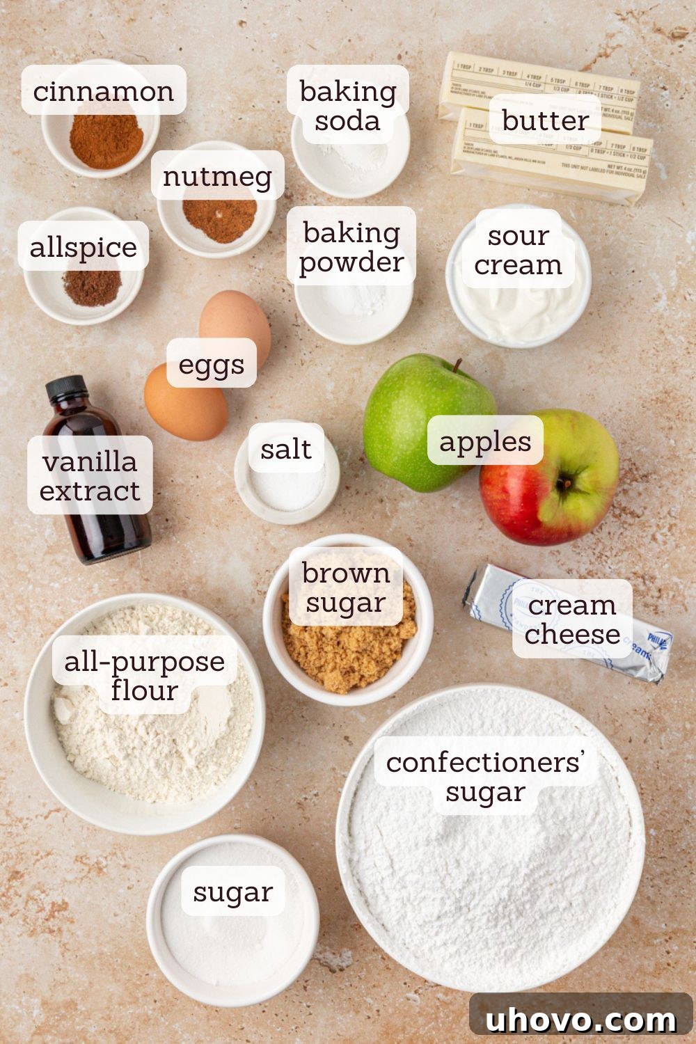 Overhead view of all the key ingredients for making delicious apple cupcakes with spiced cream cheese frosting, artfully arranged on a rustic wooden surface.
