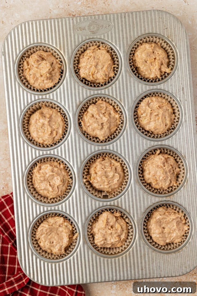 Overhead view of apple cupcake batter neatly portioned into a lined muffin pan, ready for baking.