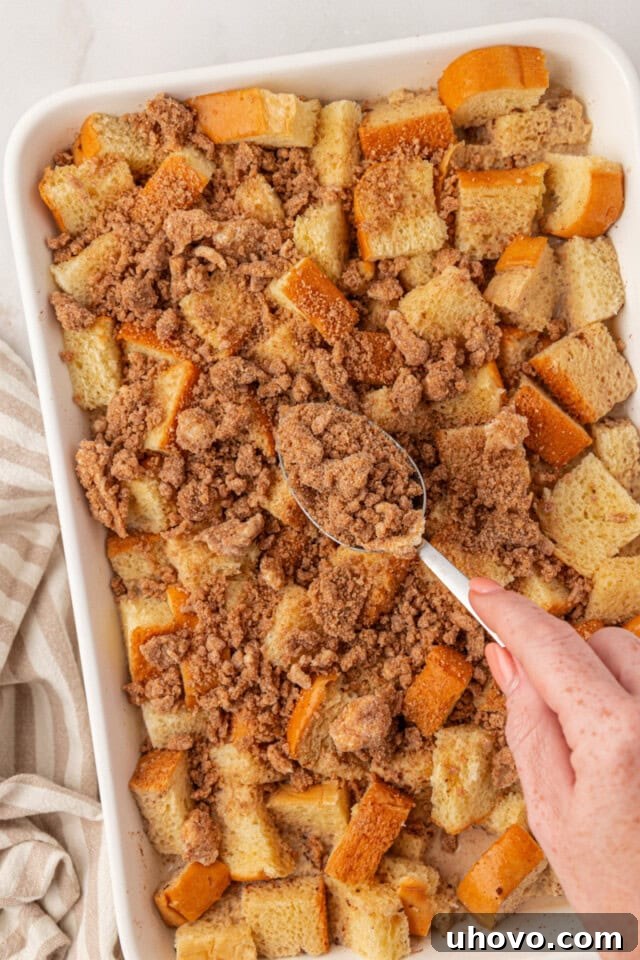overhead view of crumb topping being sprinkled over baked French toast before baking