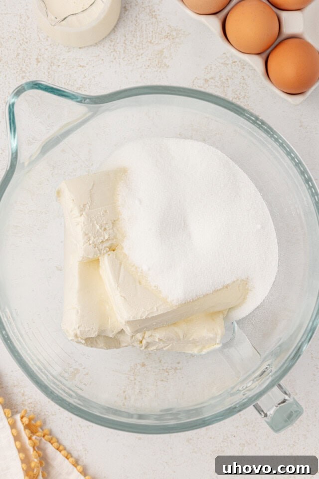 overhead view of cream cheese and sugar in a glass mixing bowl