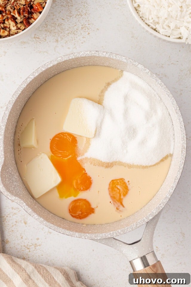 Overhead view of evaporated milk, granulated sugar, beaten egg yolks, and butter simmering gently in a saucepan for the rich frosting base.