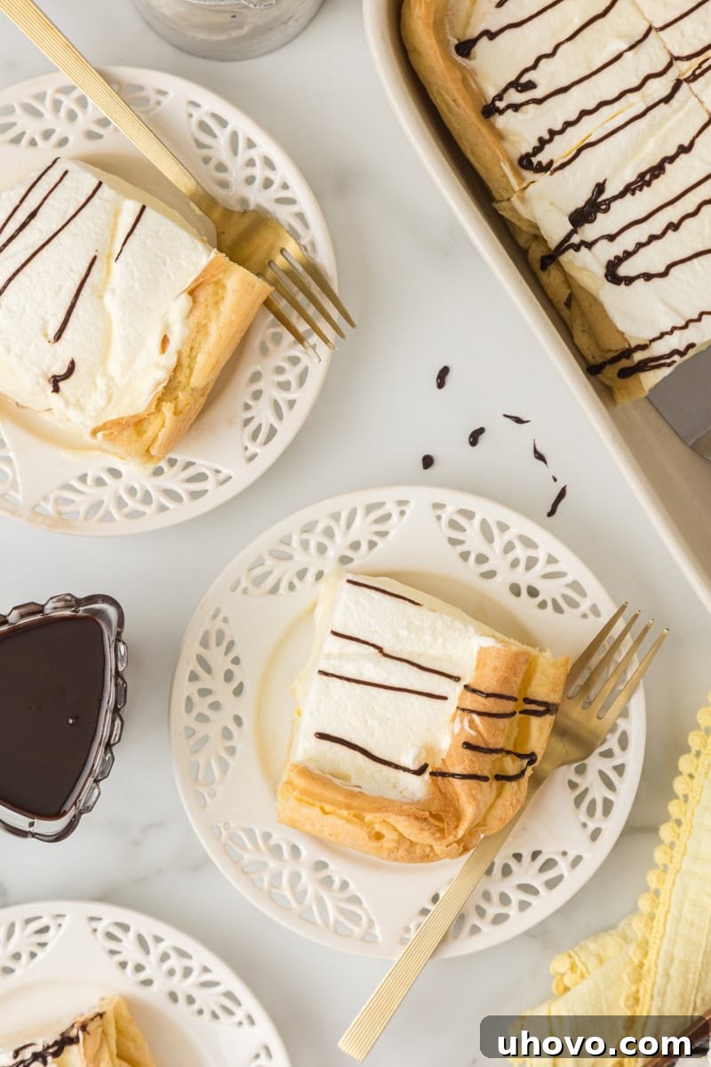 Two enticing slices of Cream Puff Cake served on individual white plates, with the remaining cake resting invitingly in the baking pan in the background.