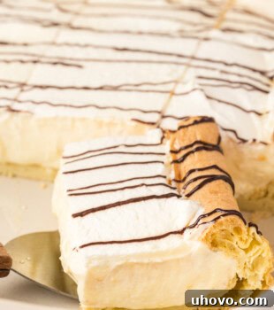 A slice of cream puff cake on a cake server resting inside the pan with the remaining cake