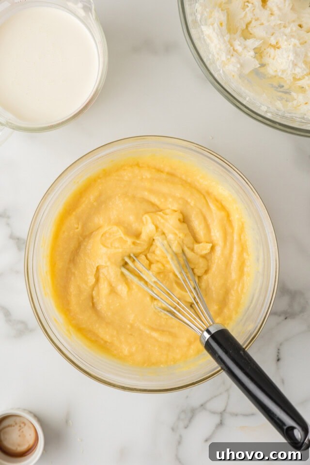 Overhead view of instant pudding mix, cold milk, and vanilla extract being whisked together in a bowl until thickened for the cake filling.
