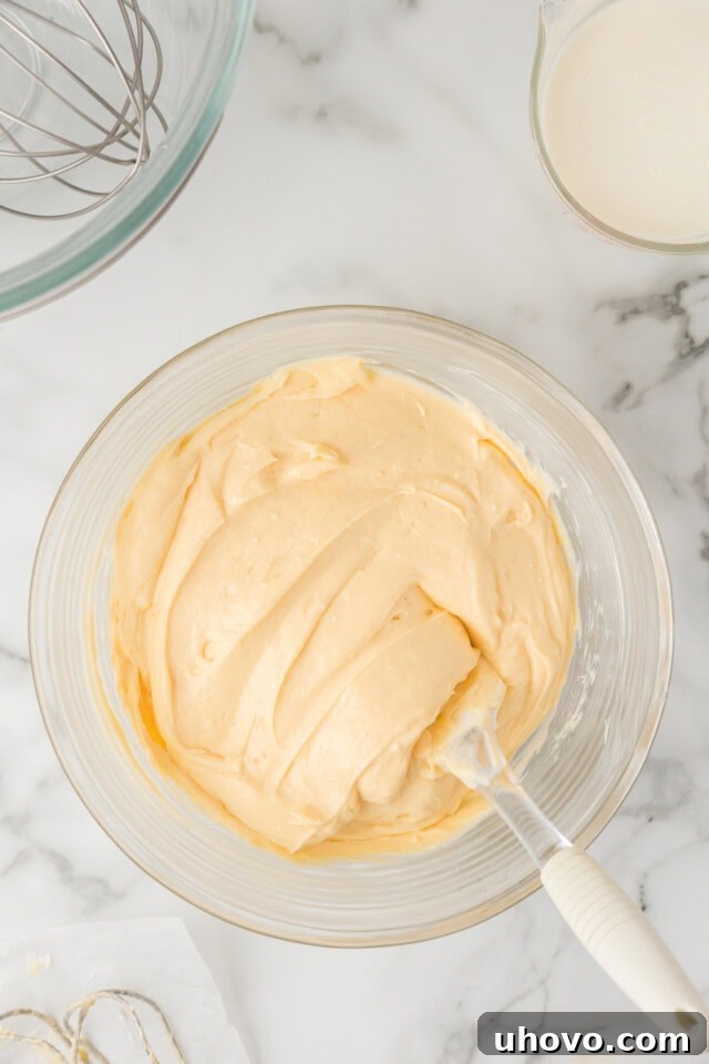 Overhead view of the thickened pudding mixture being combined with a bowl of beaten, softened cream cheese, ready to be blended into a creamy filling.