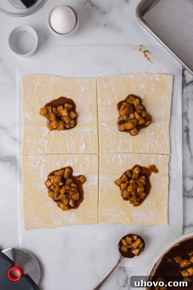 Overhead view of cooled apple filling neatly scooped onto individual squares of puff pastry.