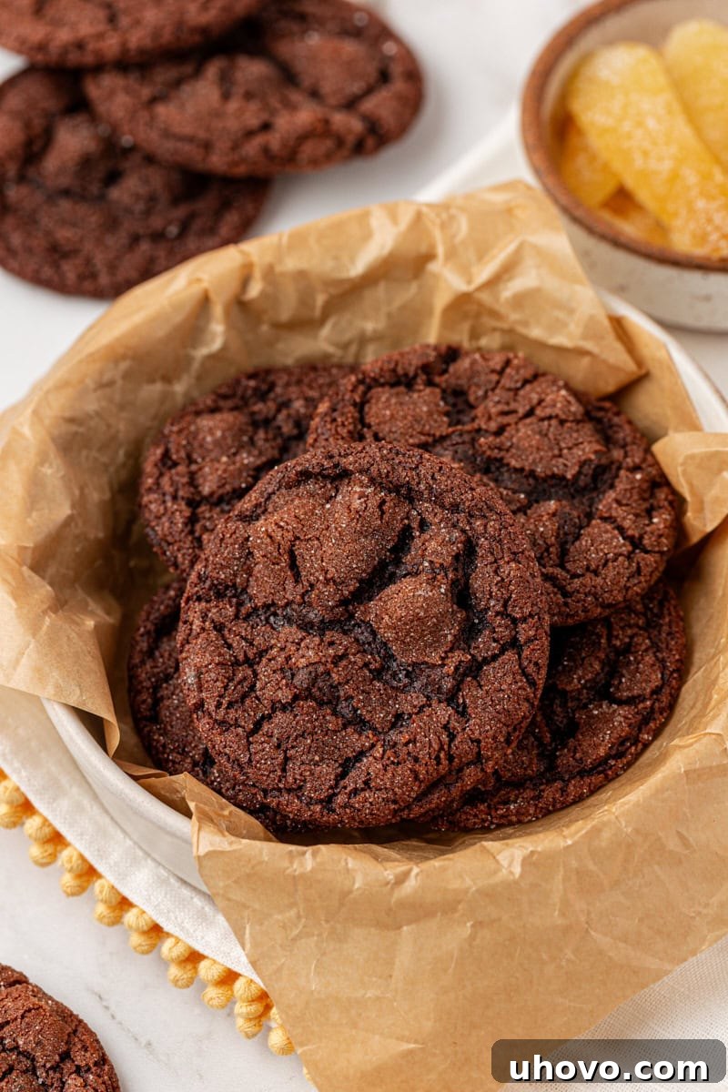 A bowl lined with parchment paper holds a generous amount of freshly baked chocolate ginger cookies, invitingly presented.