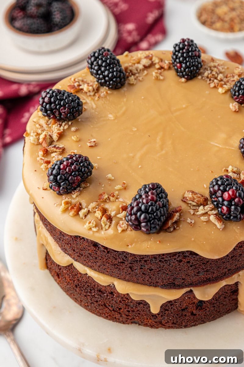 Kentucky jam cake topped with fresh blackberries and nuts, served on a marble cake stand. This cozy Southern jam cake is moist, spiced, and topped with creamy caramel frosting. A must-bake for winter!