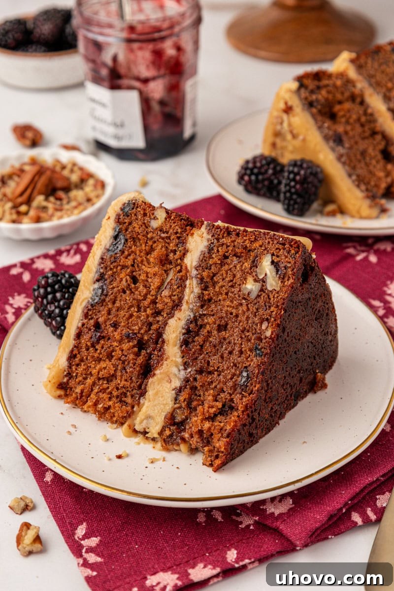 a slice of Kentucky jam cake on a white plate with more servings of cake in the background. This cozy Southern jam cake is moist, spiced, and topped with creamy caramel frosting. A must-bake for winter!