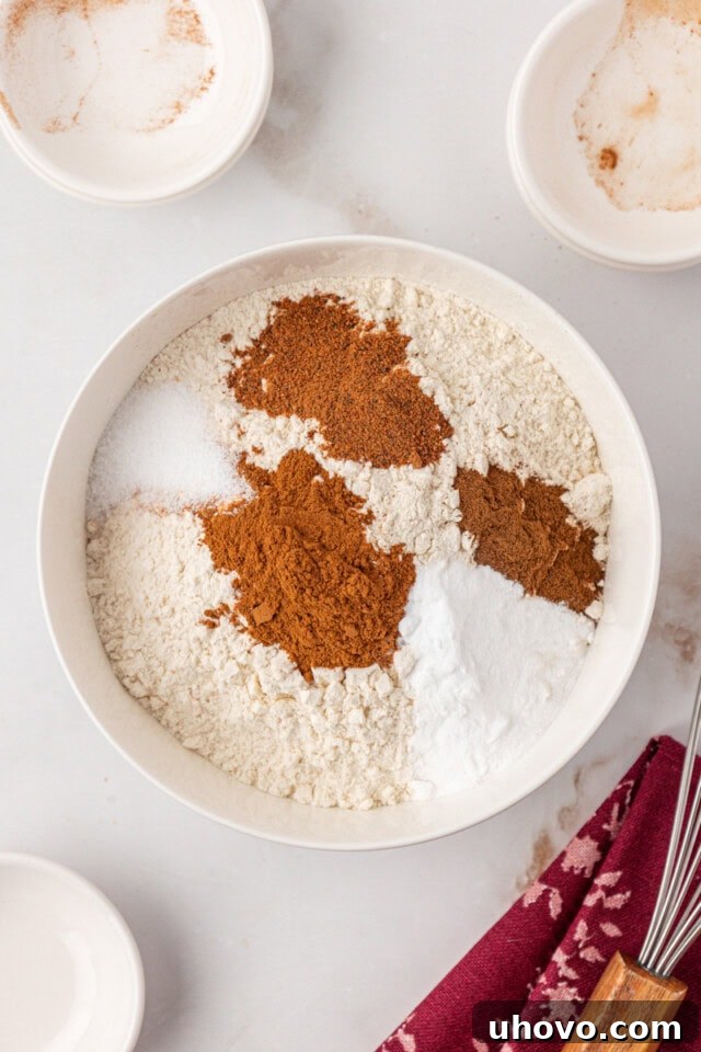 overhead view of flour, baking soda, salt, and spices in a white mixing bowl