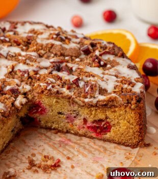 A rustic, partially sliced cranberry coffee cake on parchment paper, ready to be served.