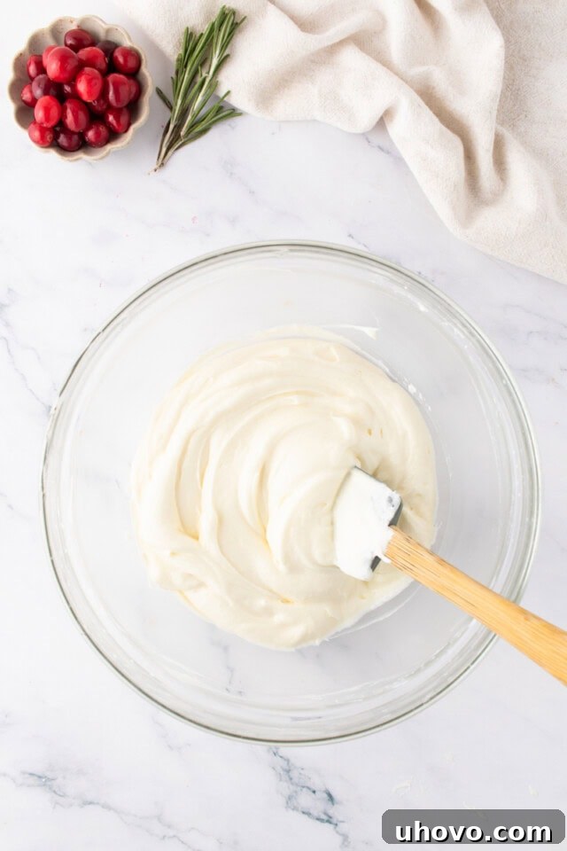 overhead view of no-bake white chocolate cheesecake mixture in a glass mixing bowl