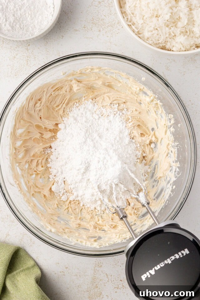 overhead view of confectioners' sugar added to cream cheese mixture for coconut snowballs