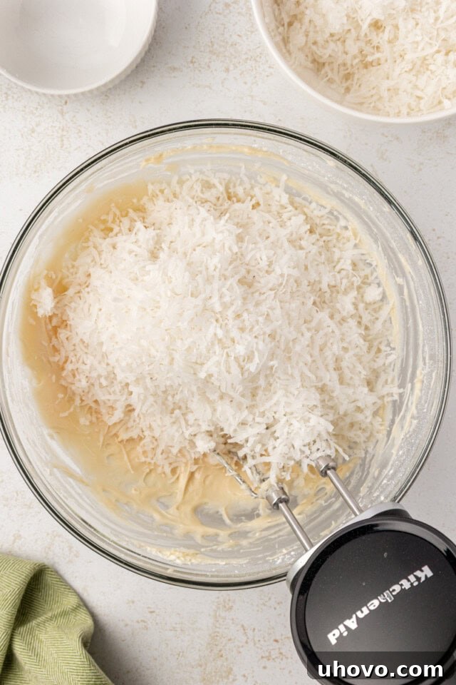 overhead view of shredded coconut added to cream cheese mixture for coconut snowballs