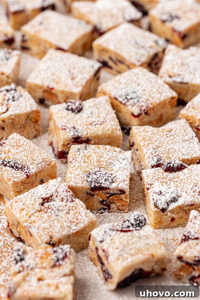 A beautiful array of Snowflake Crisp pieces, perfectly cut into squares and generously topped with a dusting of powdered sugar, showcasing their festive 'snowy' appearance.