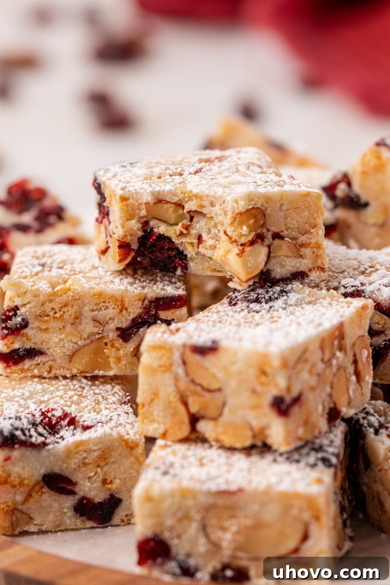 Close-up photograph of a small stack of Snowflake Crisp bars, with a bite missing from the top piece, revealing the delicious layers of white chocolate, marshmallows, crackers, and dried fruit.