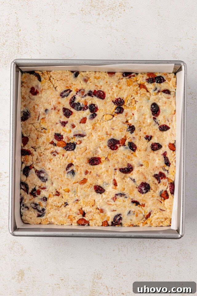 Overhead view of the Snowflake Crisp mixture neatly spread into an even layer in a parchment-lined baking pan, ready to cool and set.